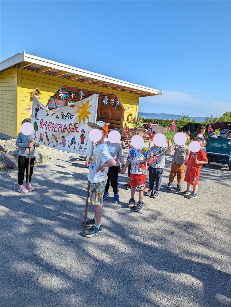 Barn står med fane, klare for å gå i 17.mai tog ved Fevåg barnehage - Klikk for stort bilde