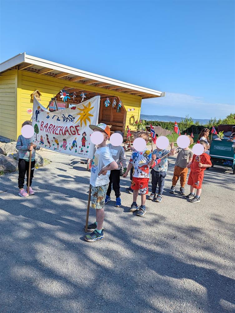 Barn står med fane, klare for å gå i 17.mai tog ved Fevåg barnehage - Klikk for stort bilde